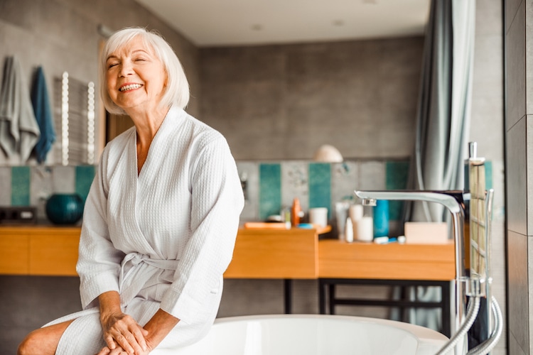 smiling senior lady bathrobe sitting on bath