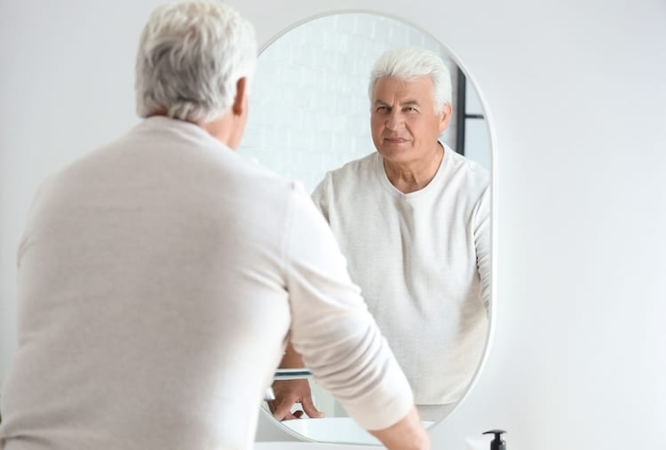 senior man looking mirror home