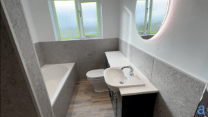 A modern finished bathroom with light grey marble-effect wall panels and wood-style flooring. The room features a white low level bathtub, a back-to-wall toilet, and a vanity unit with an integrated sink and chrome tap, situated beneath a large circular LED-illuminated mirror.