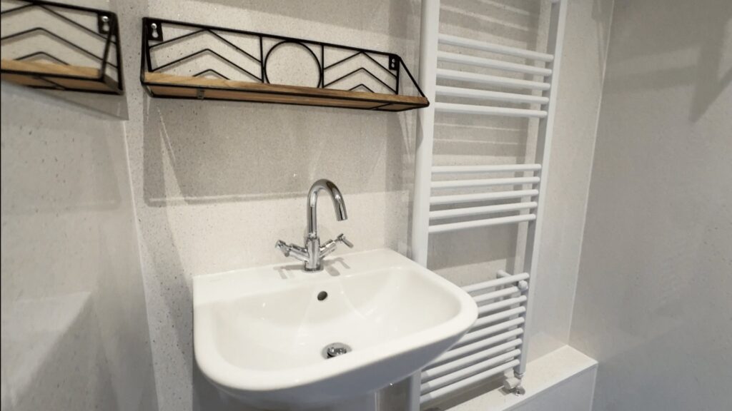 Audrey's pedestal basin with an easy-turn lever tap, beside the white heated towel rail.