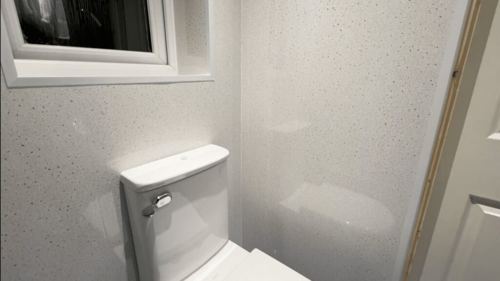 Audrey's new comfort-height toilet against easy-clean white sparkle waterproof panels.