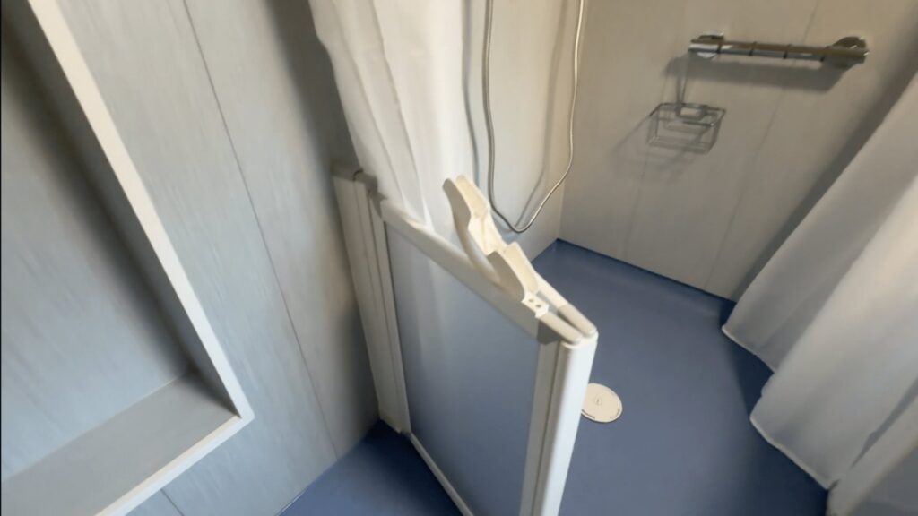The half-height shower door in Colin's wet room, with a grab rail and flush floor drain.