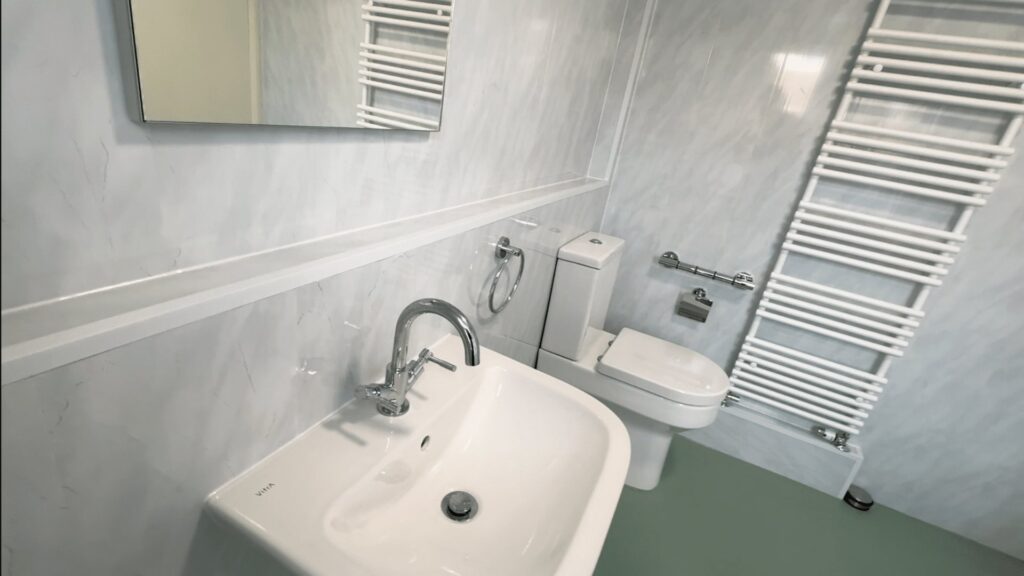 Helen's finished wheelchair-accessible wet room, with a level-access shower, half-height doors, basin and toilet