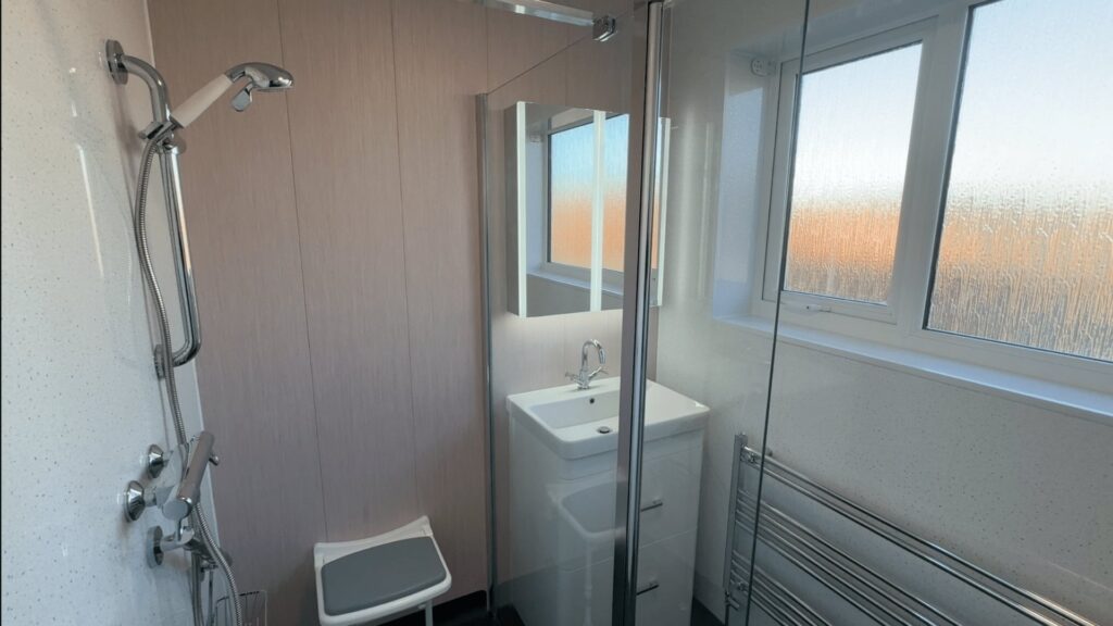 The walk-in shower in Julie's wet room, with a wall-mounted shower seat and grab rail.