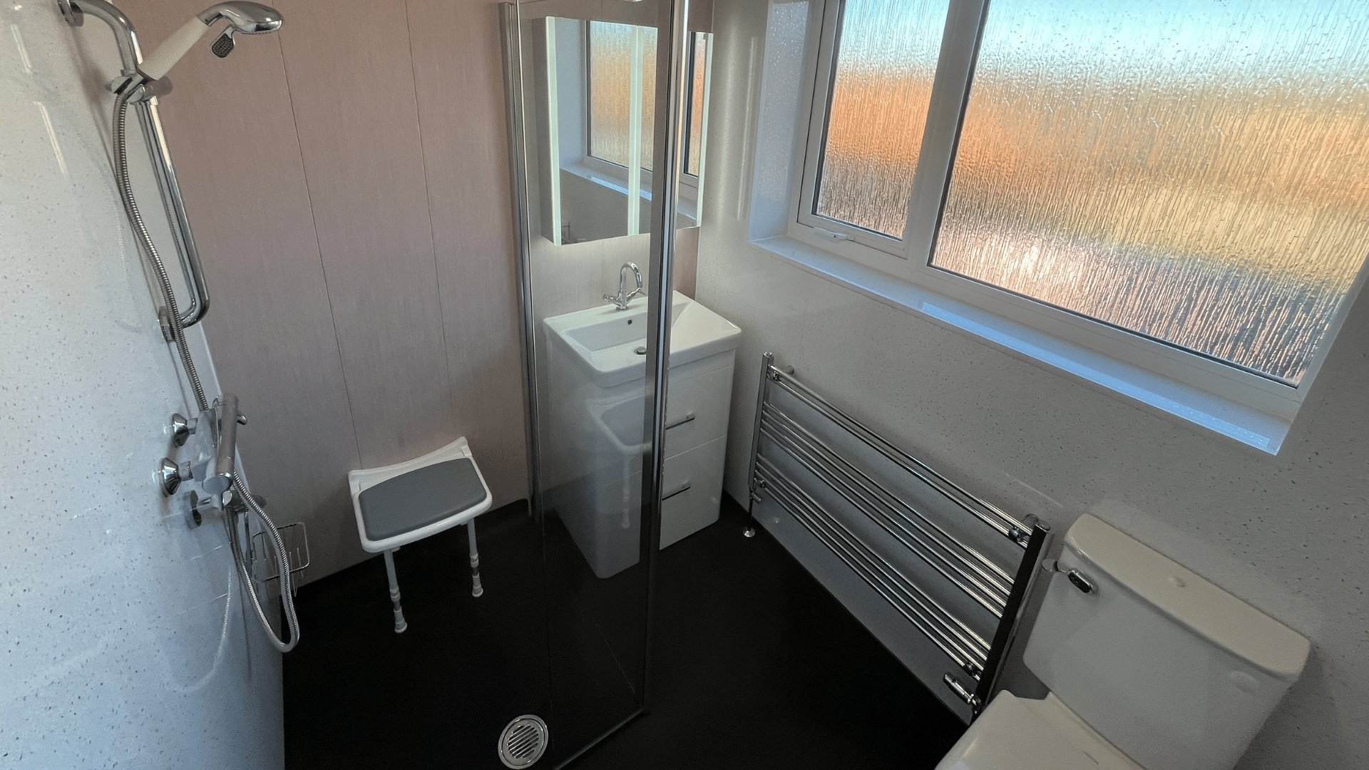 Julie's finished wet room, with a walk-in shower, shower seat, comfort-height toilet and illuminated LED mirror