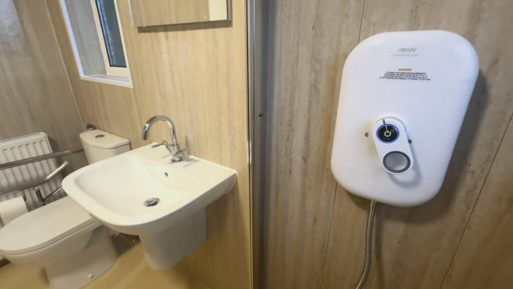 The easy-to-use AKW electric shower and the basin behind the glass safety screen