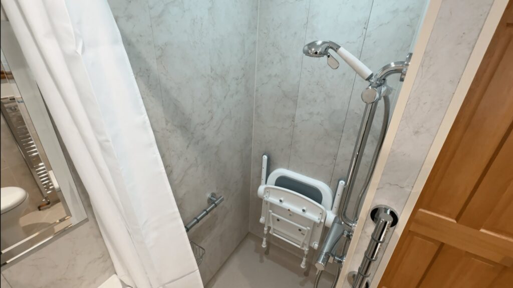 The folding shower seat with armrests and the shower on its sliding rail in Steve's wet room