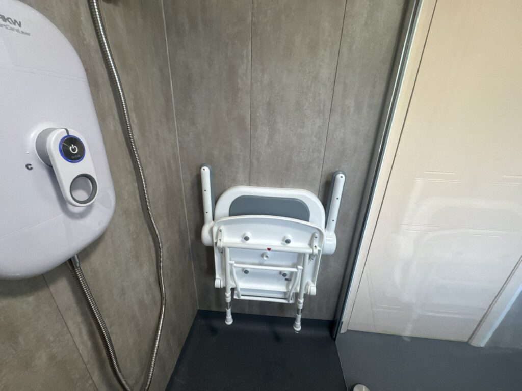 The padded fold-down shower seat with armrests and the AKW electric shower in Brian's wet room