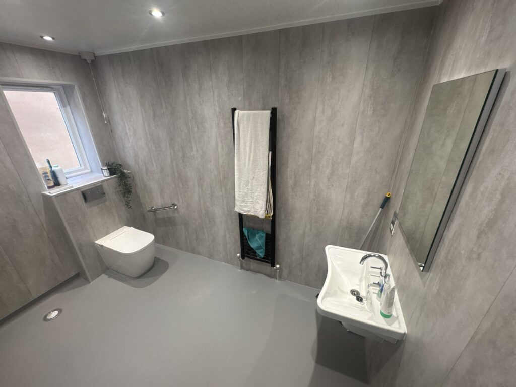 Linda's finished wheelchair-friendly wet room: open level floor, basin, toilet and heated towel rail.