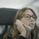 a woman in glasses talking on a phone