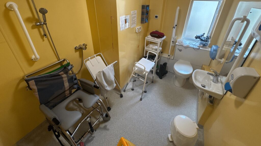 Room 1 at Horsfall House before the work, with yellow walls and mobility equipment filling the floor space.