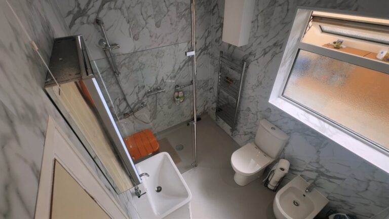 Lesley's finished wet room from above, with a level shower area, folding seat, toilet, bidet and vanity basin.