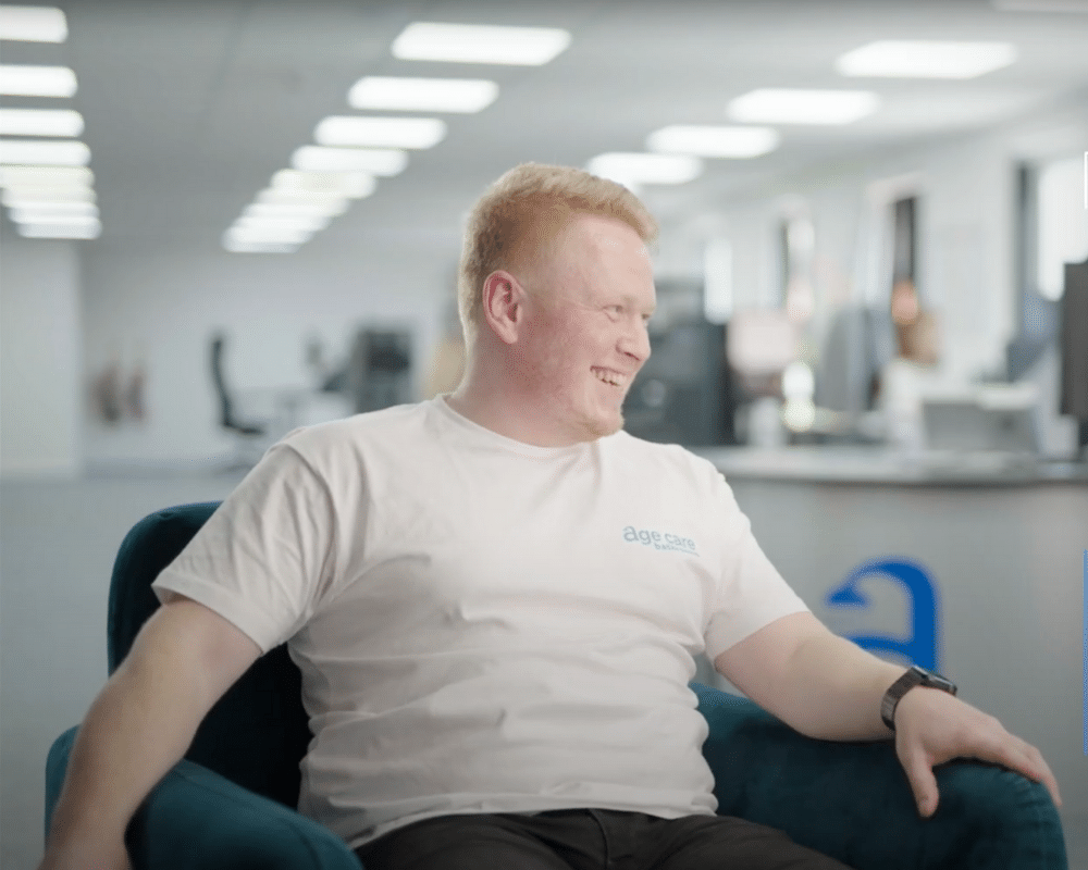 Portrait of Sam, the director of Age Care Bathrooms, smiling and sitting in a professional setting.