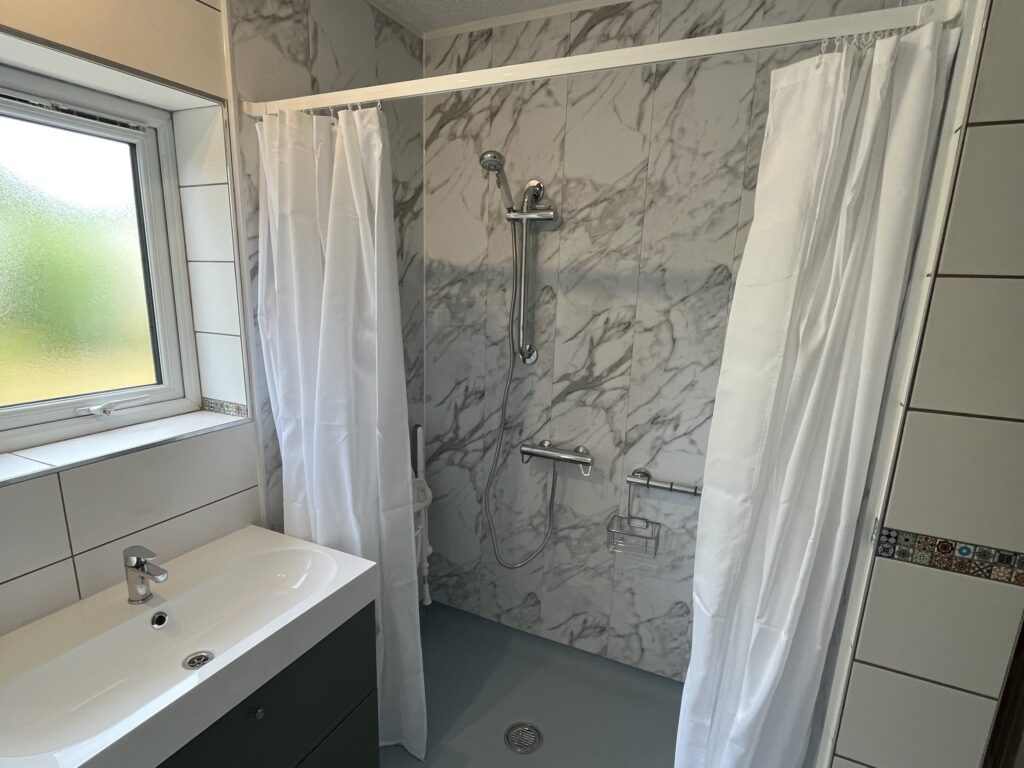 The level-access shower in Sandra's wet room, with a thermostatic shower, Grab n Grip rail and curtains.