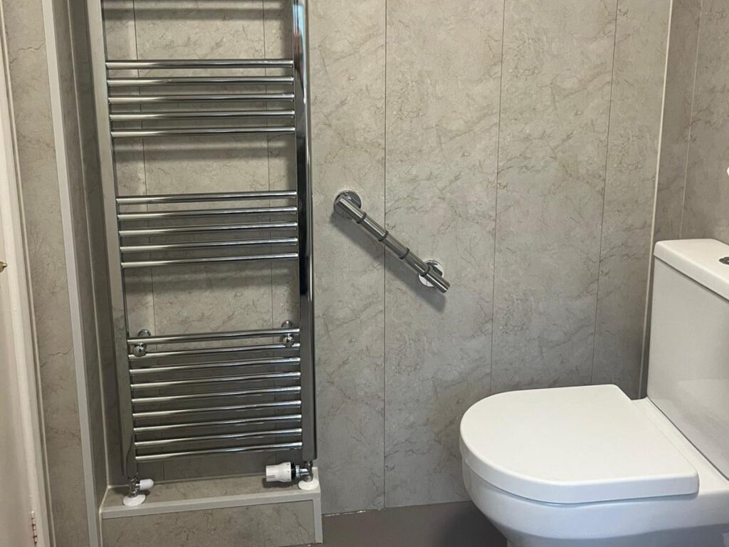 The chrome heated towel rail and grab rail beside the toilet in Julie's wet room.