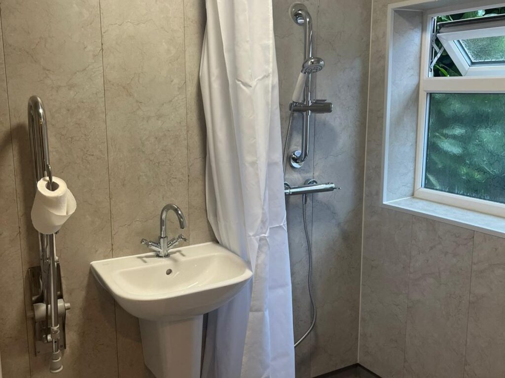 Julie's finished wet room: level-access shower with grab rail, basin and curtain, with no steps anywhere.