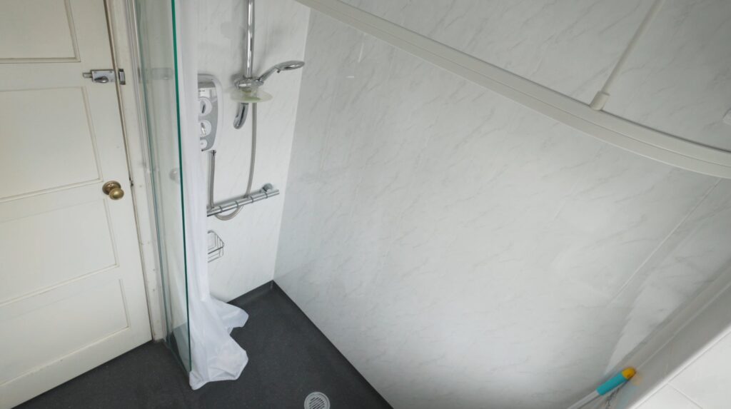 Peter's new wet room shower: an electric shower, grab rail and handheld head over a level, step-free floor with a flush drain.