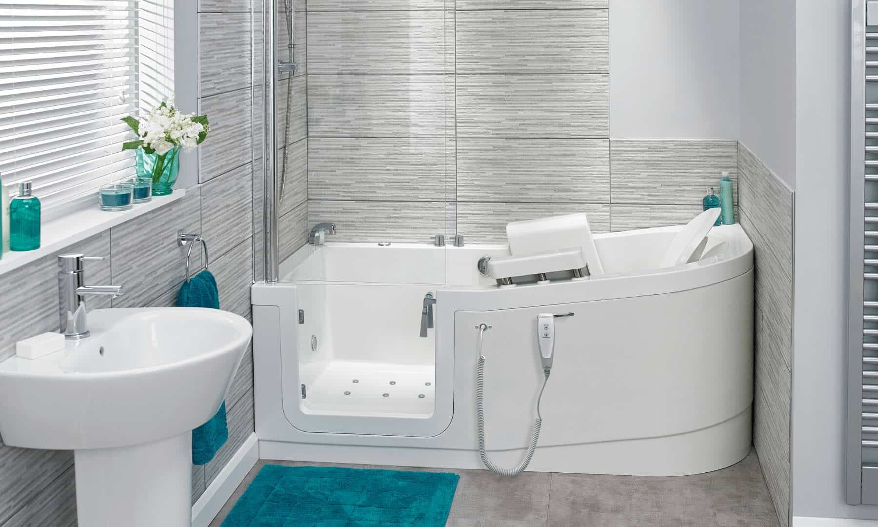 Modern bathroom with a walk-in bathtub featuring a door, seat, and handheld shower; white sink, teal towel and rug, turquoise accents, and gray tiled walls.