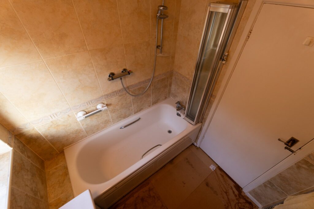 Edward's old bathroom before the work, with a standard bath, over-bath shower and folding screen he had to climb over.