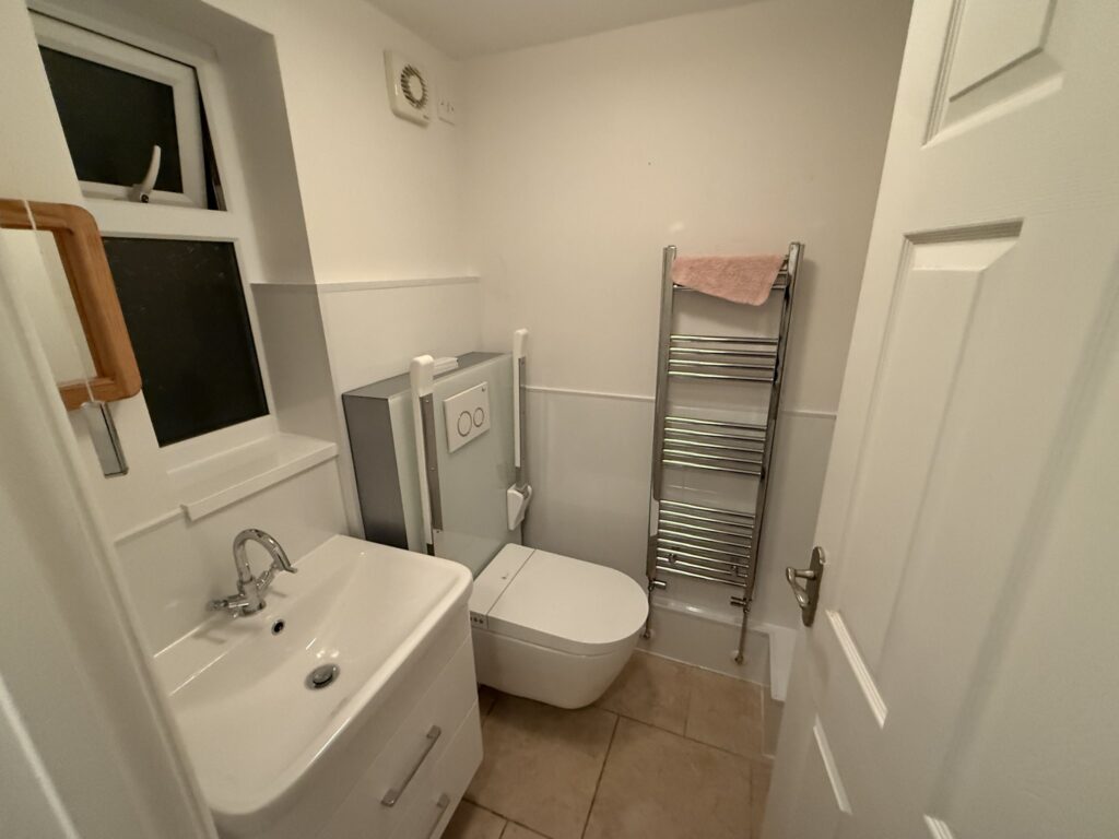 Brent's finished bathroom: rise and fall toilet with fold-down rails, vanity basin and heated towel rail.
