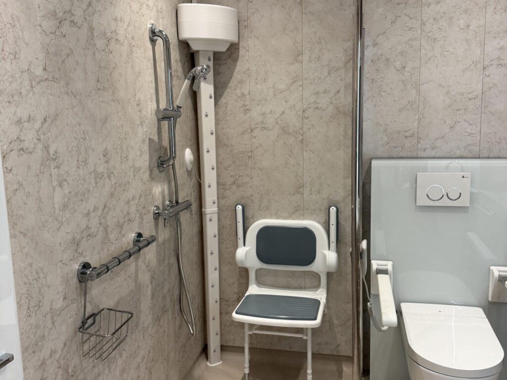 Clare's finished wet room, with a level-access shower, body dryer, folding padded seat and wall-hung rise and fall toilet.