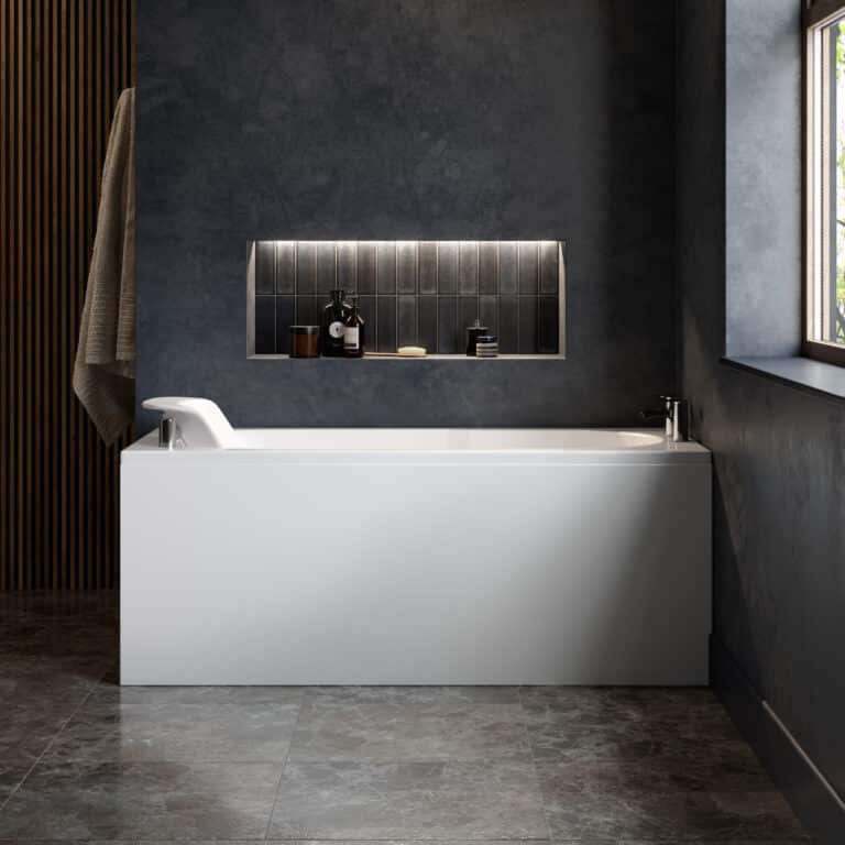 A side-angle view of a modern accessible bathroom featuring an Omega walk-in bath with the powered seat lift fully lowered into the tub. Only the white, curved headrest of the seat remains visible above the rim of the bath at one end. The stylish setting includes dark grey textured walls, large marble-effect floor tiles, and a lit recessed shelf containing various toiletries.