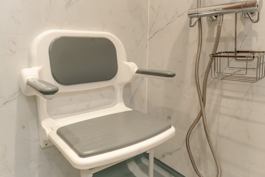 The padded fold-down shower seat with armrests in Dominic's wet room.