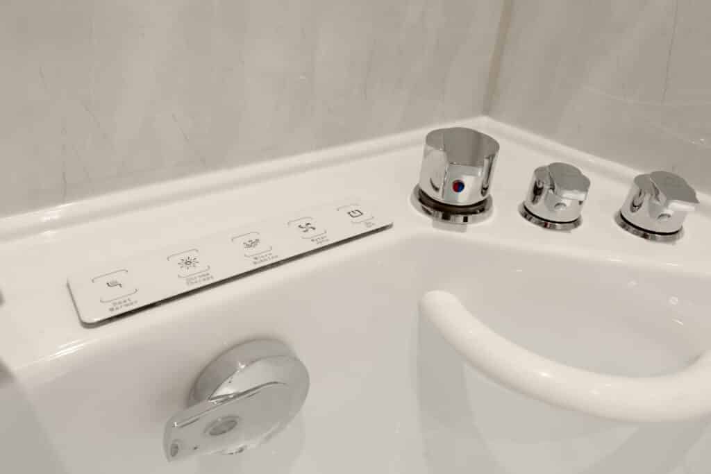 Close-up of the chrome control dials and push-button panel for a whirlpool walk-in bath installed by Age Care Bathrooms, showing easy-to-use accessibility features.