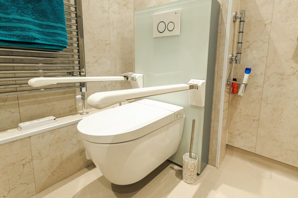 Olivia's wall-hung rise and fall toilet with fold-down support rails on both sides.