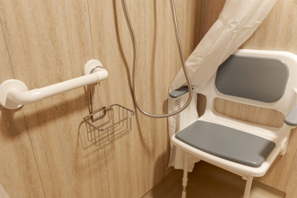 The padded fold-down shower seat in Samantha's wet room, with a grab rail and shower basket within easy reach.