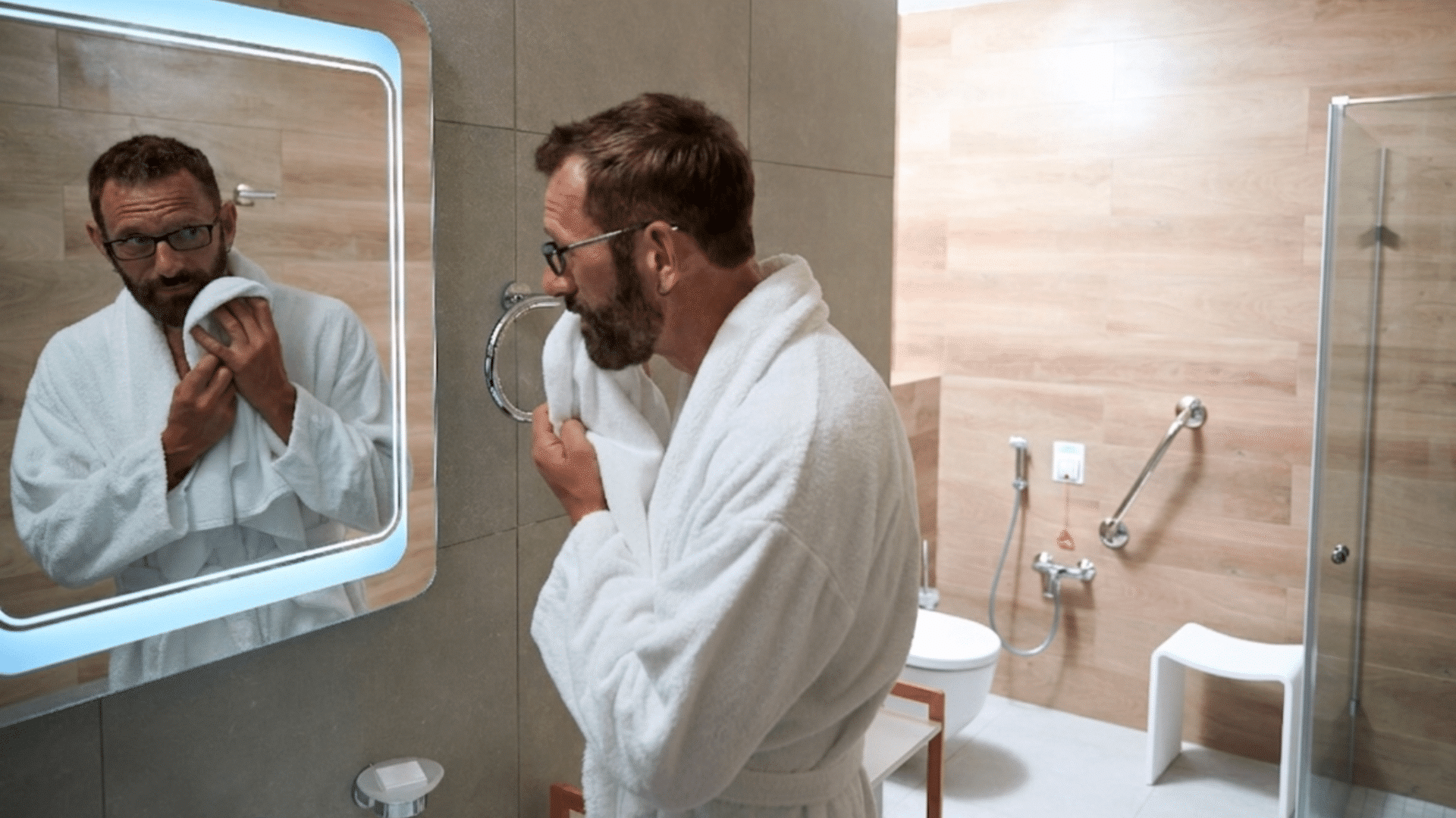 A person stood looking into the mirror in their accessible bathroom that has many adaptations.