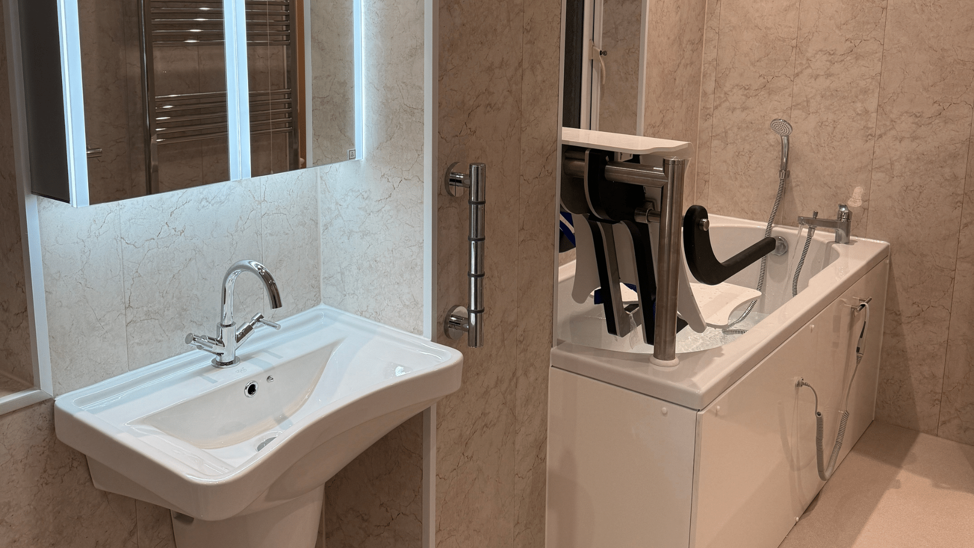 Omega walk-in bath with a powered seat lift next to a white sink in a marbled tiled bathroom.