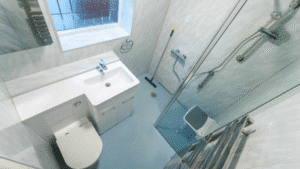 Top-down view of a modern wet room with a walk-in shower, safety seat, vanity, and toilet.