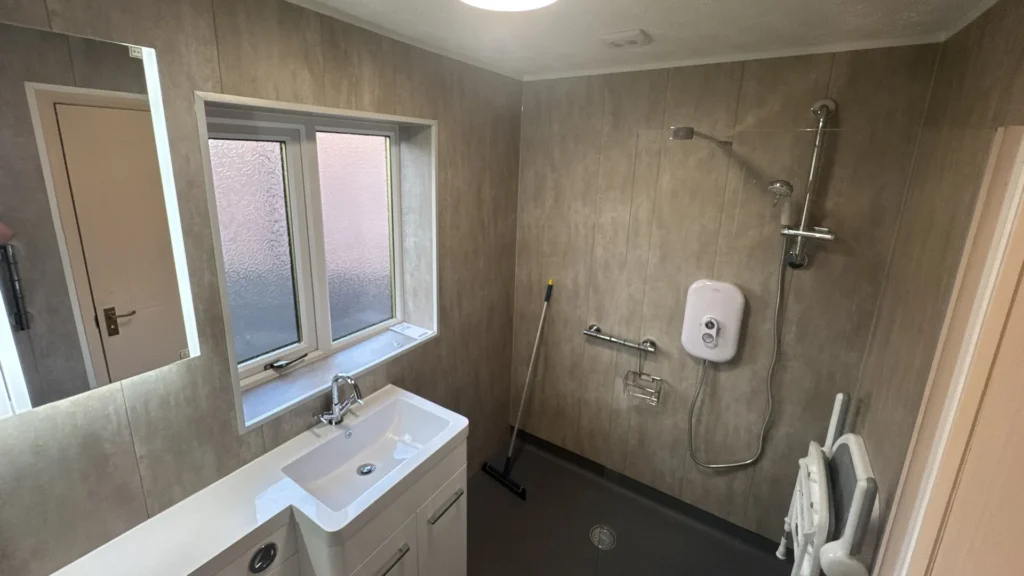 Wet room by Age Care Bathrooms, with a level floor, fold-down shower seat and riser rail shower.
