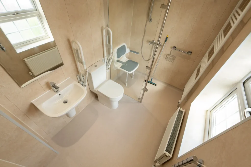 Elena's level-access wet room with a folding shower seat, toilet and grab rails