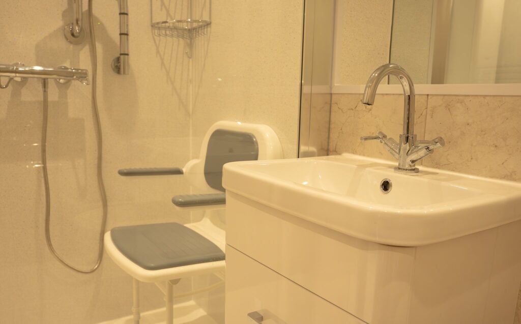 The easy-reach basin in Maya's bathroom, with the fold-down shower seat and thermostatic shower beyond.