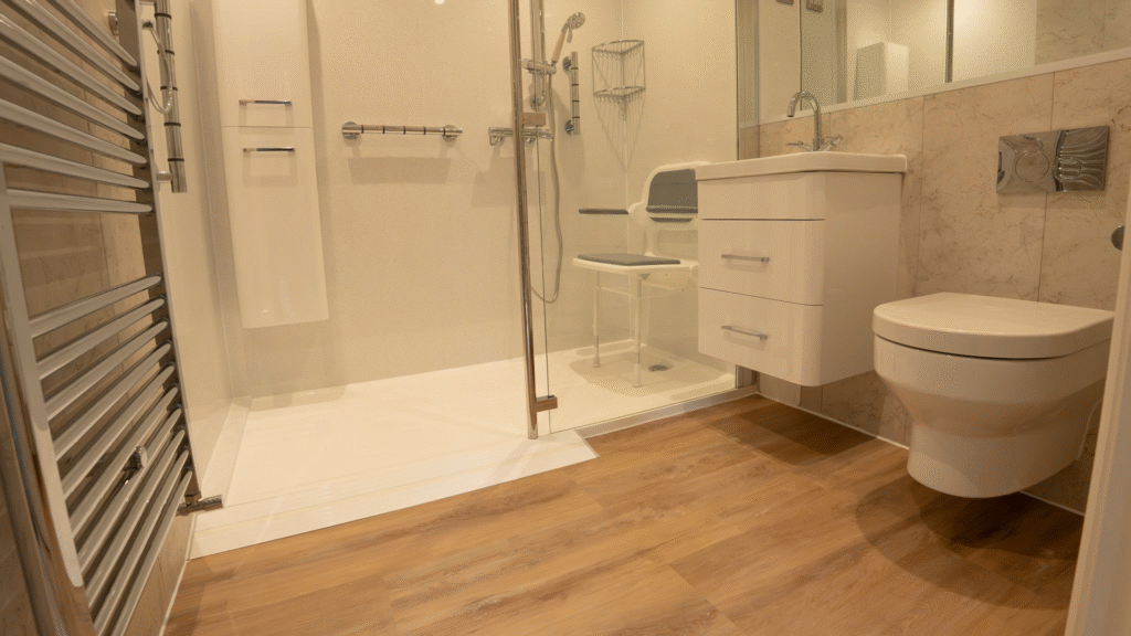 Walk-in shower room installed by Age Care Bathrooms, with a low-profile tray, glass screen, fold-down shower seat and grab rails.