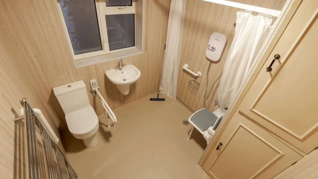 Level-access wet room by Age Care Bathrooms, with a fold-down shower seat and grab rails.