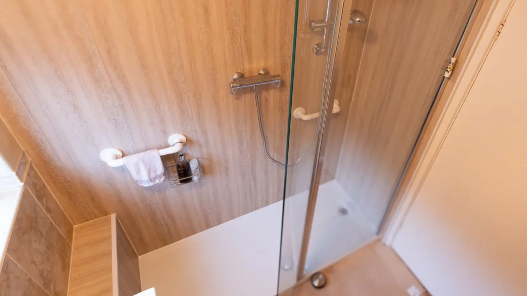 Low-step tray walk-in shower installed by Age Care Bathrooms, with grab rails and a glass screen.
