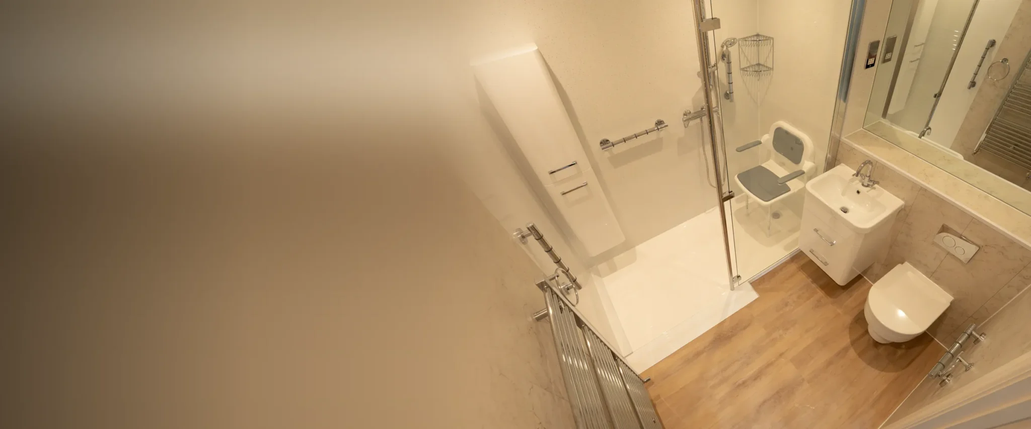 Maya’s walk-in shower, fitted by our team: a low-level tray with a glass screen, a fold-down shower seat with arms, grab rails and a thermostatic shower