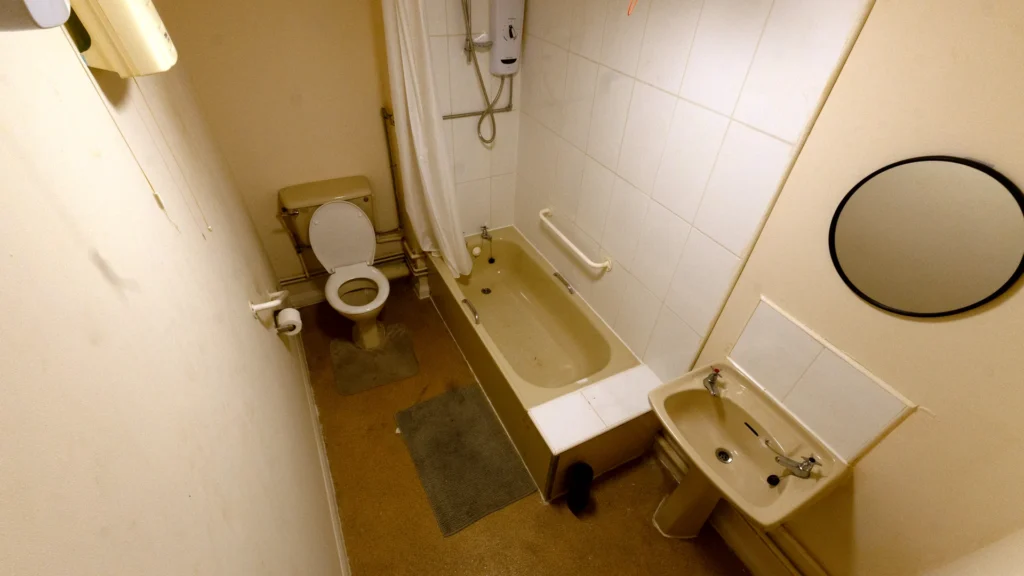 Malcom's old bathroom with a beige bath, over-bath electric shower, toilet and basin