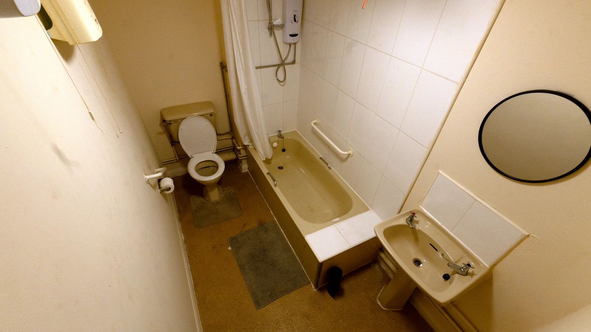 Malcom's old bathroom with a beige bath, over-bath electric shower, toilet and basin
