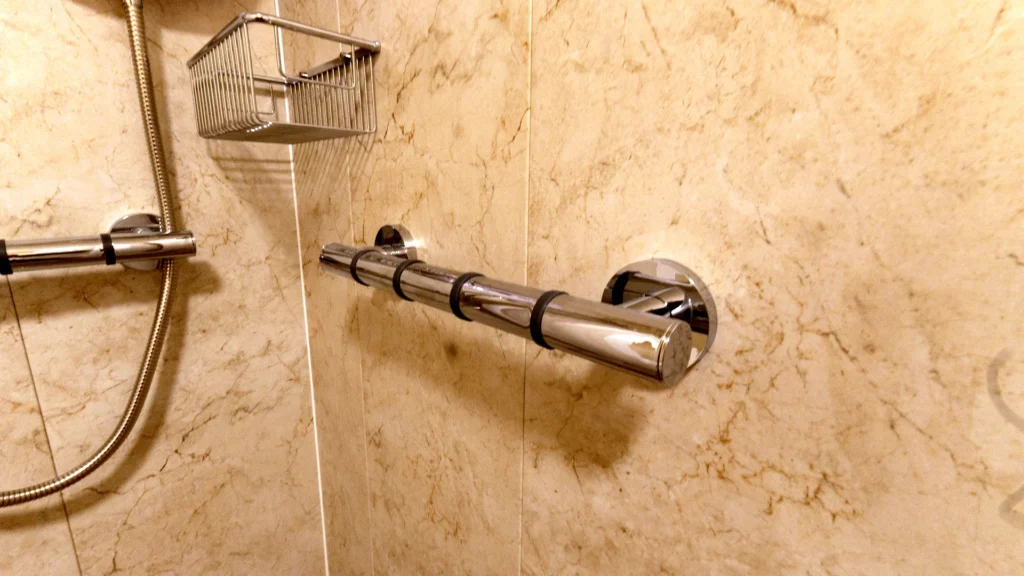 Chrome grab rail and shower riser on the marble-effect wall of Malcom's shower